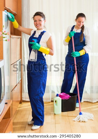 Happy adult professional cleaners washing apartment with rag and mop