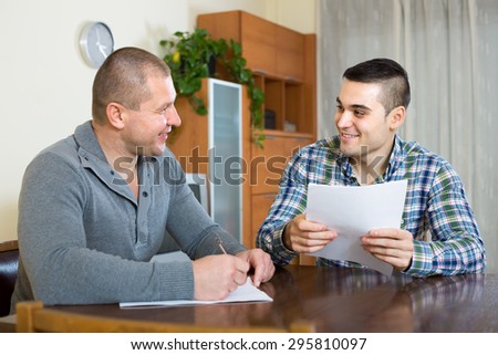 Smiling male agent consulting client about terms of contract at the table at home