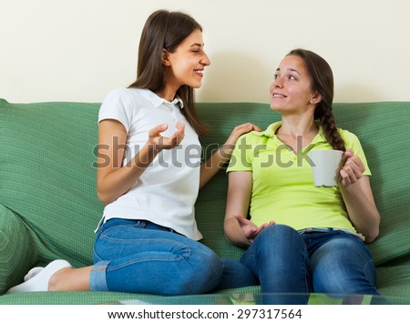 Two young women enjoying a conversation in the living room at home