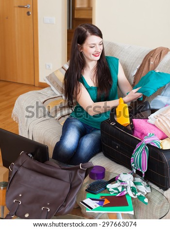Happy brunette woman packing suitcases at home going on holiday