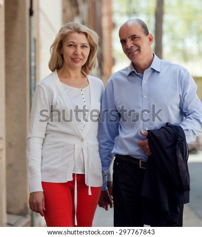 Walking through street senior family couple holding hands of each and talking