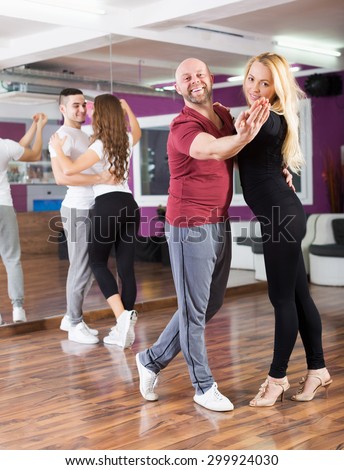 Cheerful couples enjoying of partner dance and smiling indoor