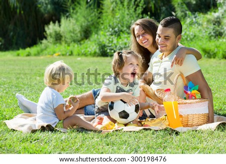 Young parents with children having picnic outdoor on sunny day