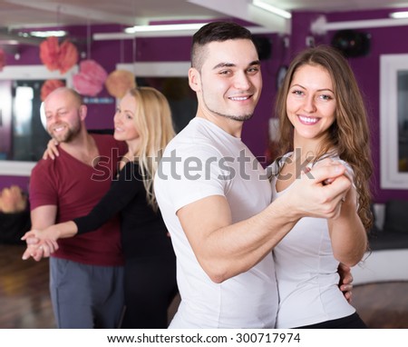 Two smiling couples having dancing class in club