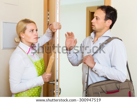 Angry young woman threatens with rolling-pin for a frightened man