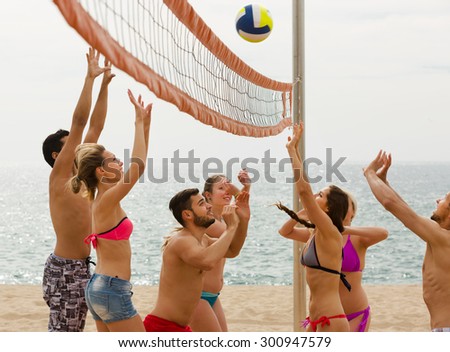 smiling adults throwing ball over net and laughing