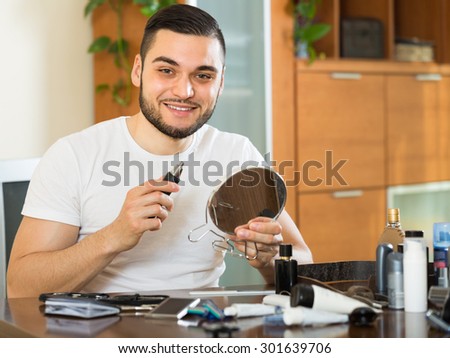 Young smiling guy using trimmer for removing hair in his nose