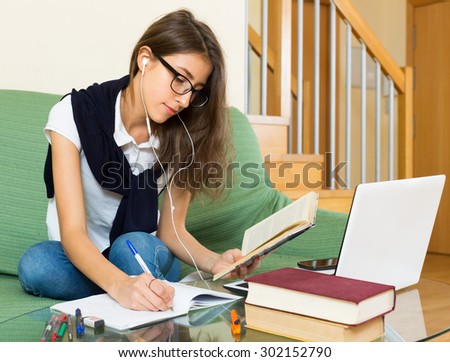 Smiling young girl writing in exercise-book at home