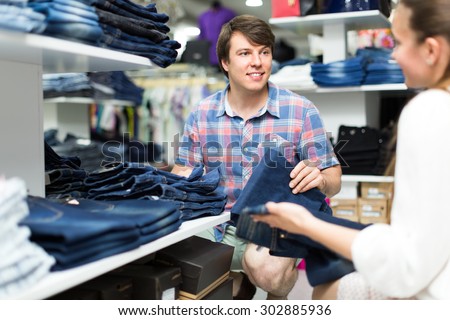 Man and woman choosing blue denim from a shelf in department store