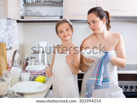 Funny playful girl helping mother to do dishes manually