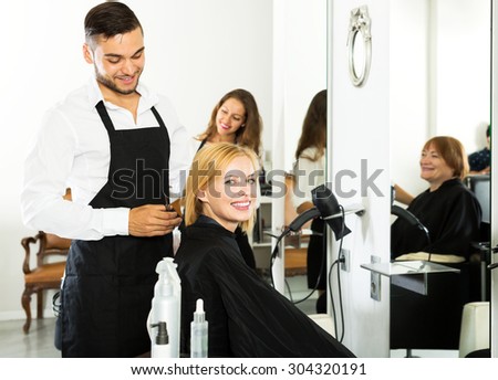 Hair stylist working on haircut for beautiful girl. Focus on the woman