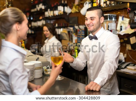 Handsome bartender giving a young woman a glass of white wine