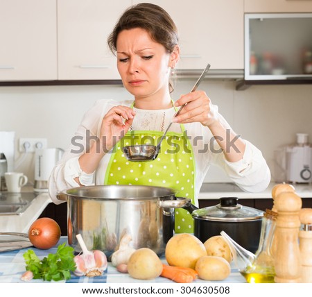Young housewife feeling bad smell from pan at the home kitchen