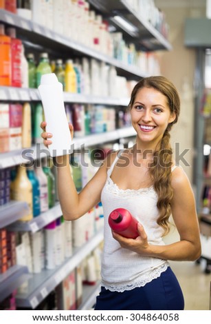 Young smiling girl buying shampoo in shopping mall