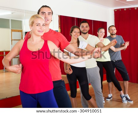 smiling young adults dancing salsa in club