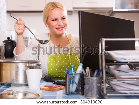 freelancer 25 years old with dishware working on PC at kitchen