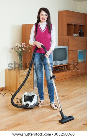 Long-haired brunette woman cleaning living room