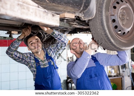 portrait smiling two men in coveralls working at auto repair shop