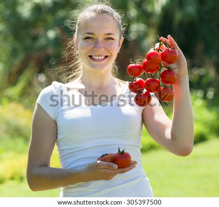 Young woman with  harvested tomato in garden