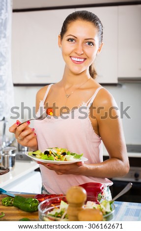 Young positive woman enjoying vegetable salad and smiling