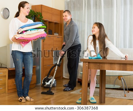 Happy smiling family of three cleaning in the living room all together