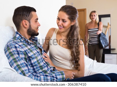 Upset blonde young woman watching how young husband is cheating