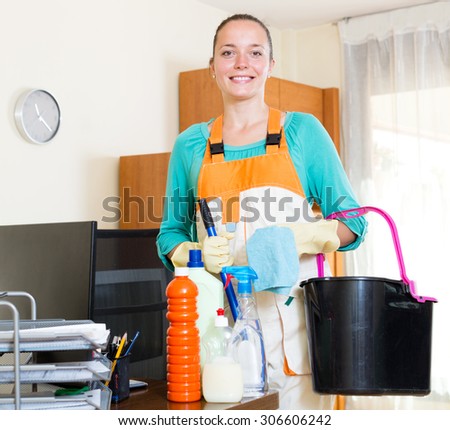Portrait cheerful young female professional cleaner cleaning office room