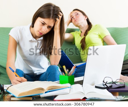 Dreary teenage student girls study at home with books and computers