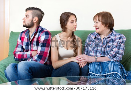 Mature woman comforts sad daughter in living room