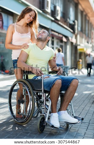 Handsome woman and her disabled husband in wheelchair outdoor