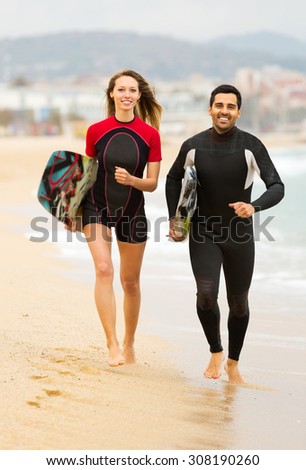 Cheerful family on the shore in wetsuits with surf boards