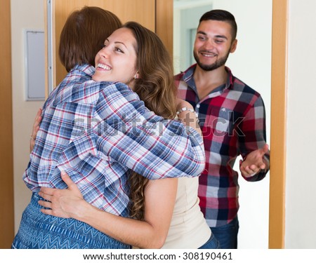 Mature woman meeting  young couple at the door