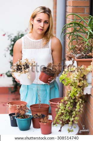 Portrait of unhappy girl discovering shrunken plants at terrace