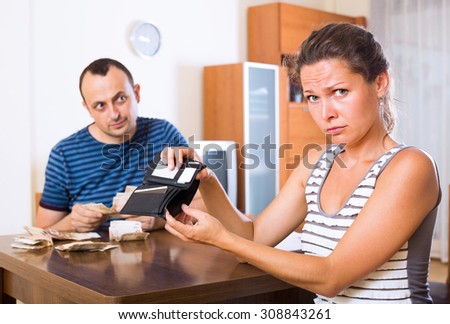 Sad young woman and her husband counting money for paying debts