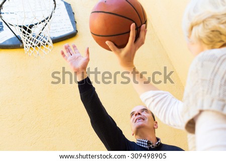 Happy mature couple throwing the ball into basket