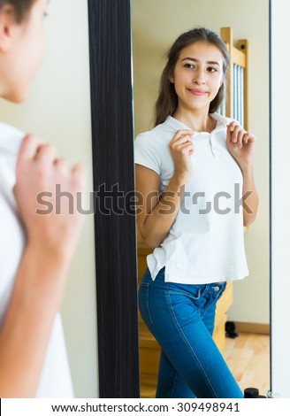 Smiling young girl trying on a t-shirt in front if the mirror
