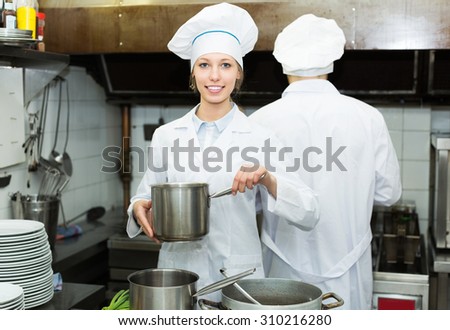 Young head-cooks cooking at professional kitchen in the restaurant