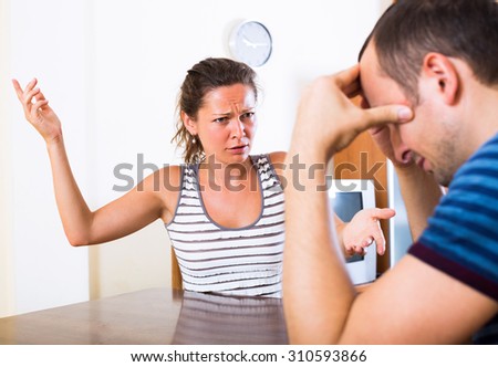 Angry young woman and her tired husband quarreling at home