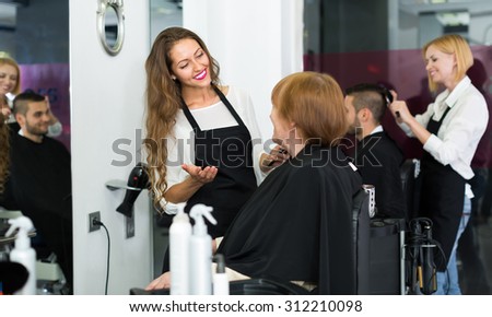 Portrait of smiling senior woman cutting her hair at the hairdressing salon
