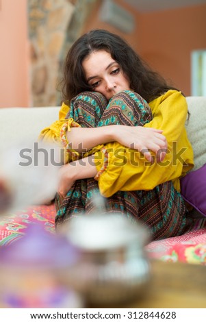 Sad and lonely woman sitting on couch at home