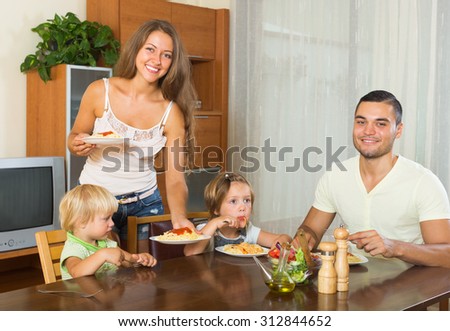 happy family of four  having lunch with  italian pasta at home together