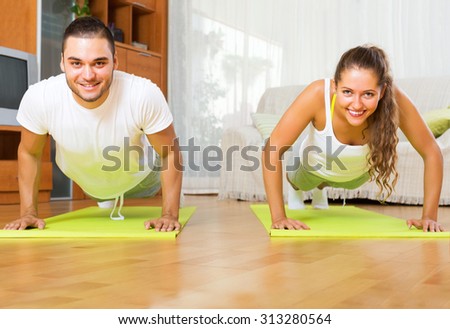 Smiling people doing yoga on mats in room