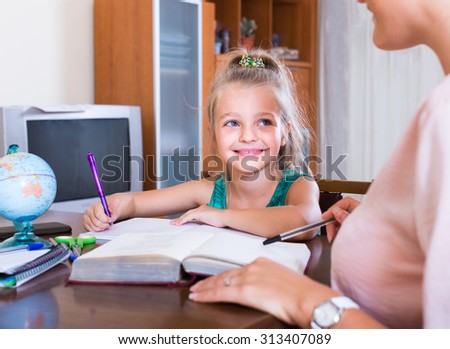 Private positive teacher and little girl studying with notes at home