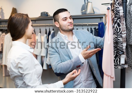 Young store clerk serving purchaser at fashionable apparel store