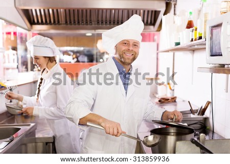 Cheerful cooks cooking at professional kitchen in the take-away  restaurant