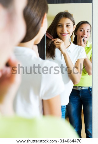 Smiling young woman making make-up near mirror