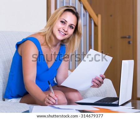 Happy spanish female student studying with laptop and notes indoors