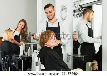 Elderly woman cuts hair at the hair salon with  barber