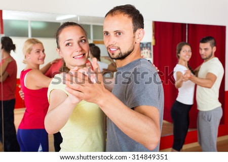 Smiling men and women enjoying of partner dance in class