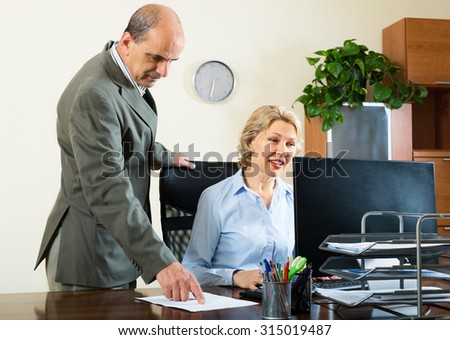Ordinary office scene with two elderly and serious co-workers